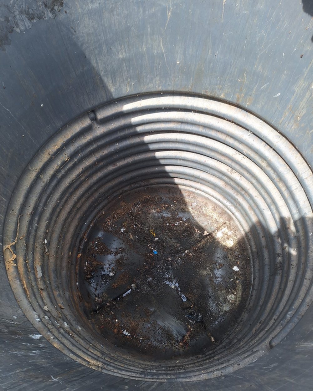 Fond d'une cuve de conteneur semi-enfoui chargé de jus de déchets